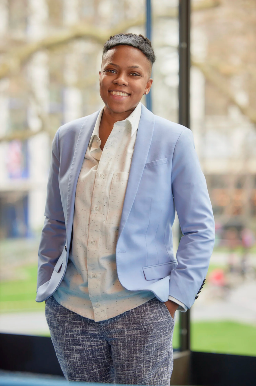 Professional in light blue blazer and patterned pants stands confidently.