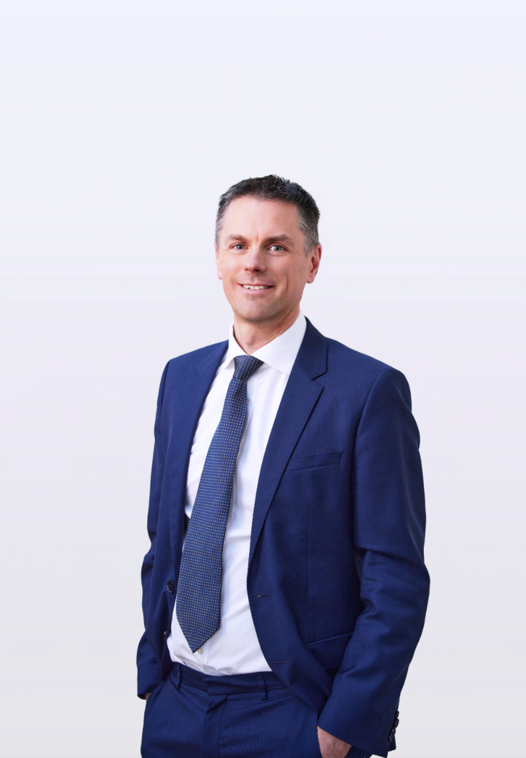 Professional in navy suit and tie poses against white background.