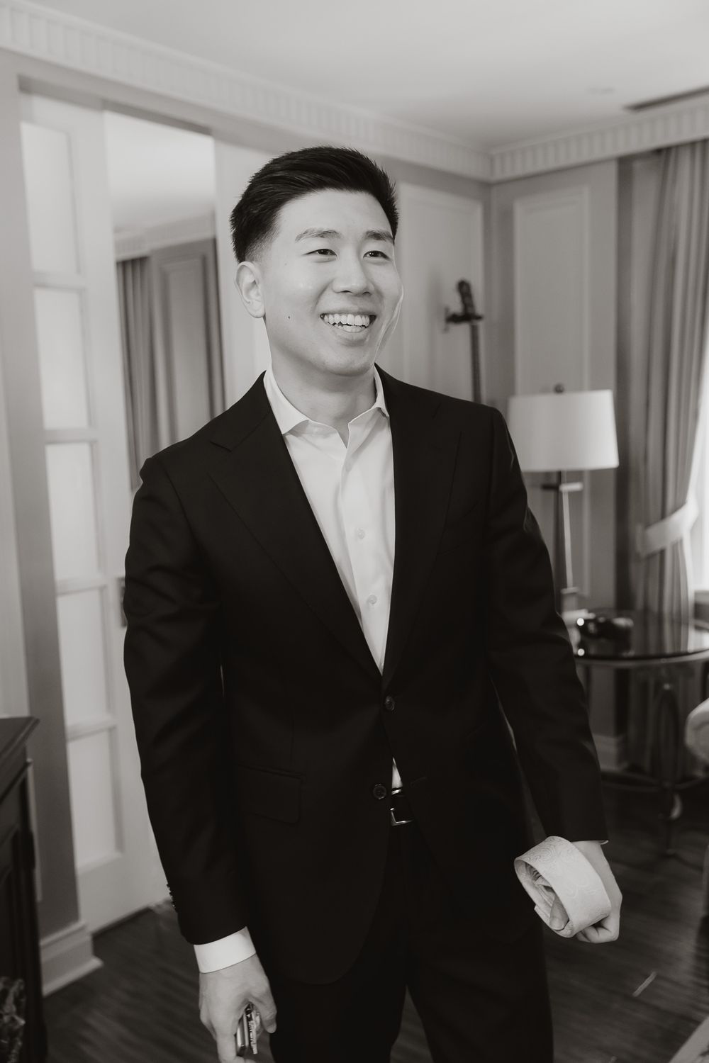 Professional portrait of person in dark suit smiling in elegant room setting.