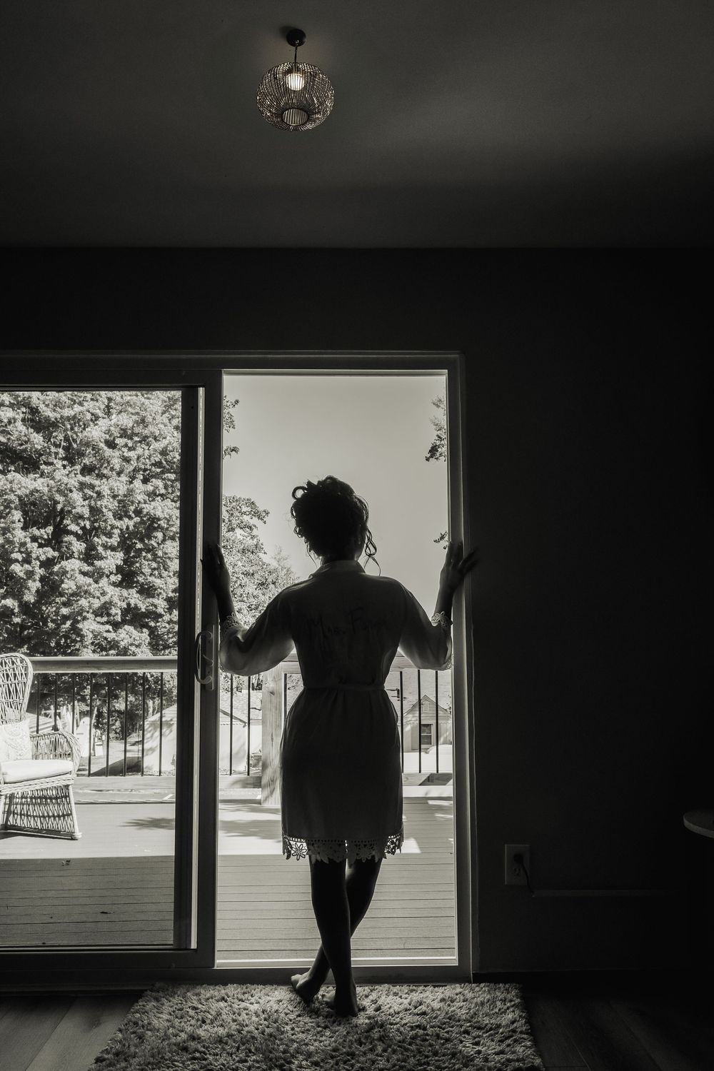 A silhouetted figure stands in a doorway against bright daylight, creating a dramatic black and white contrast.