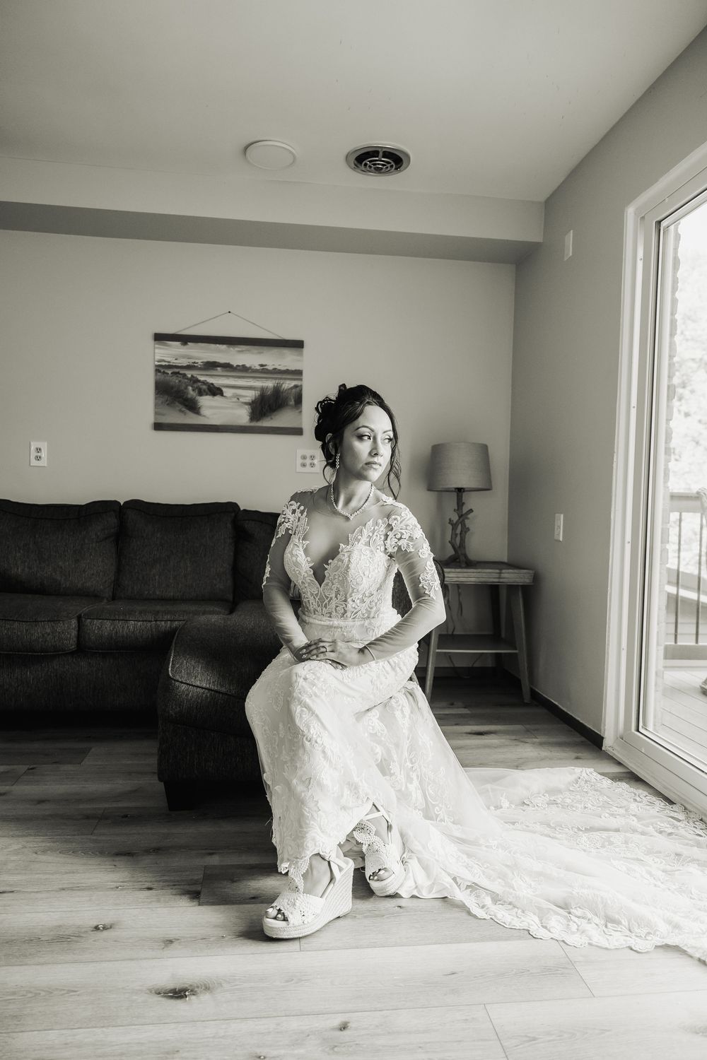 A series of black and white photos showing someone in an elegant white lace wedding dress sitting on a light wood floor.
