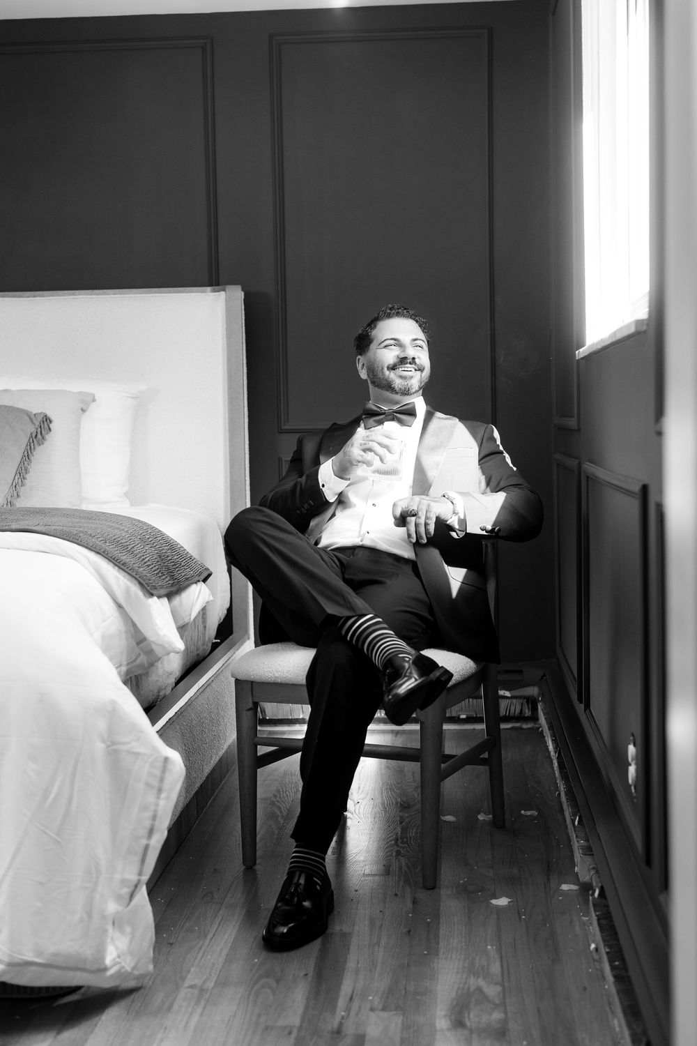 A black and white photo series shows someone lounging and moving positions on a white couch in an empty room.
