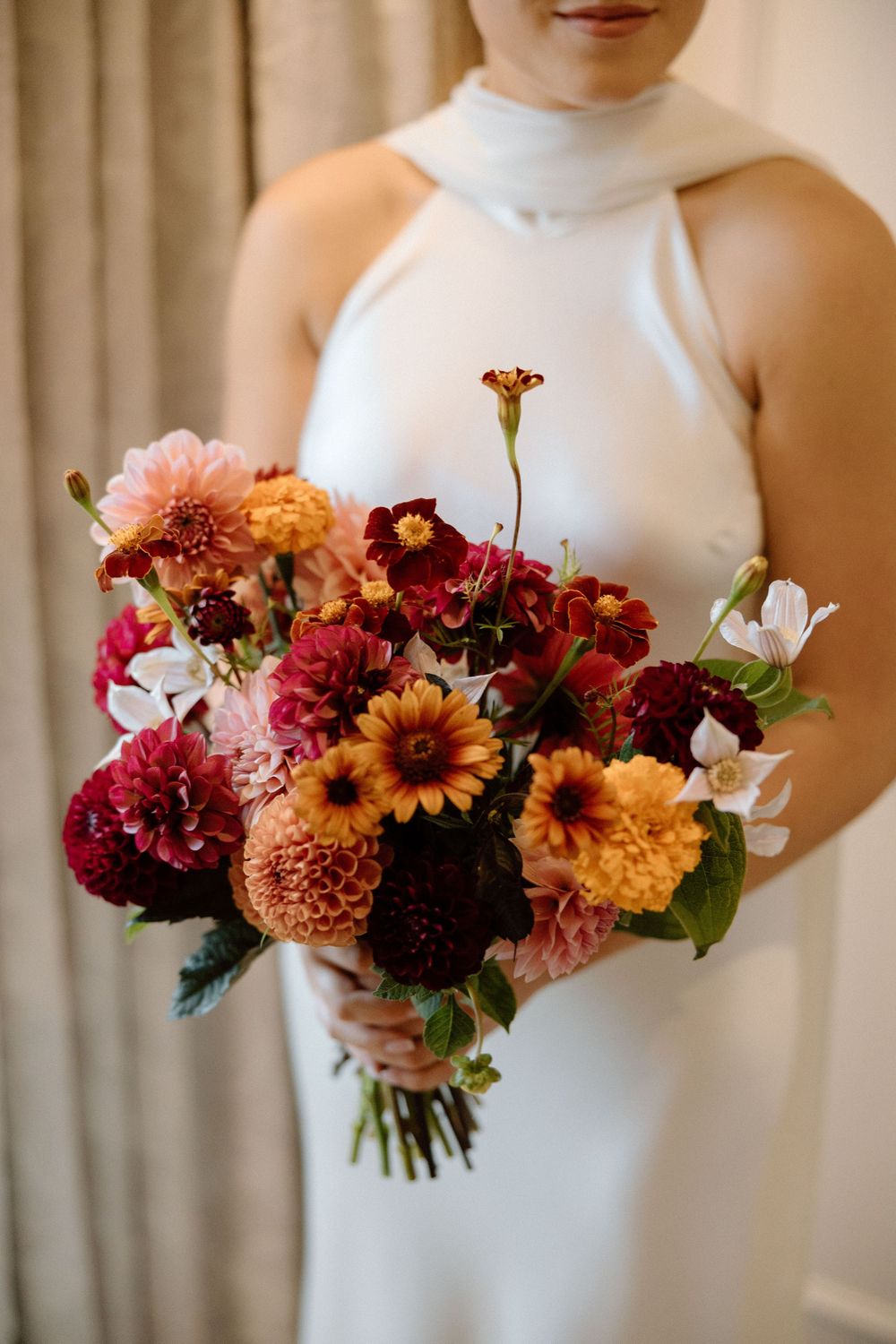 Three bouquets of vibrant autumn-colored flowers featuring dahlias, sunflowers and other seasonal blooms against a light background.