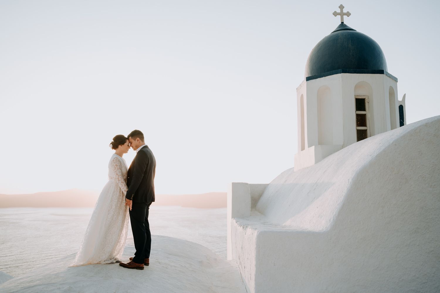 A romantic portrait of a bride and groom against sunset after their elopement in Santorini Greece