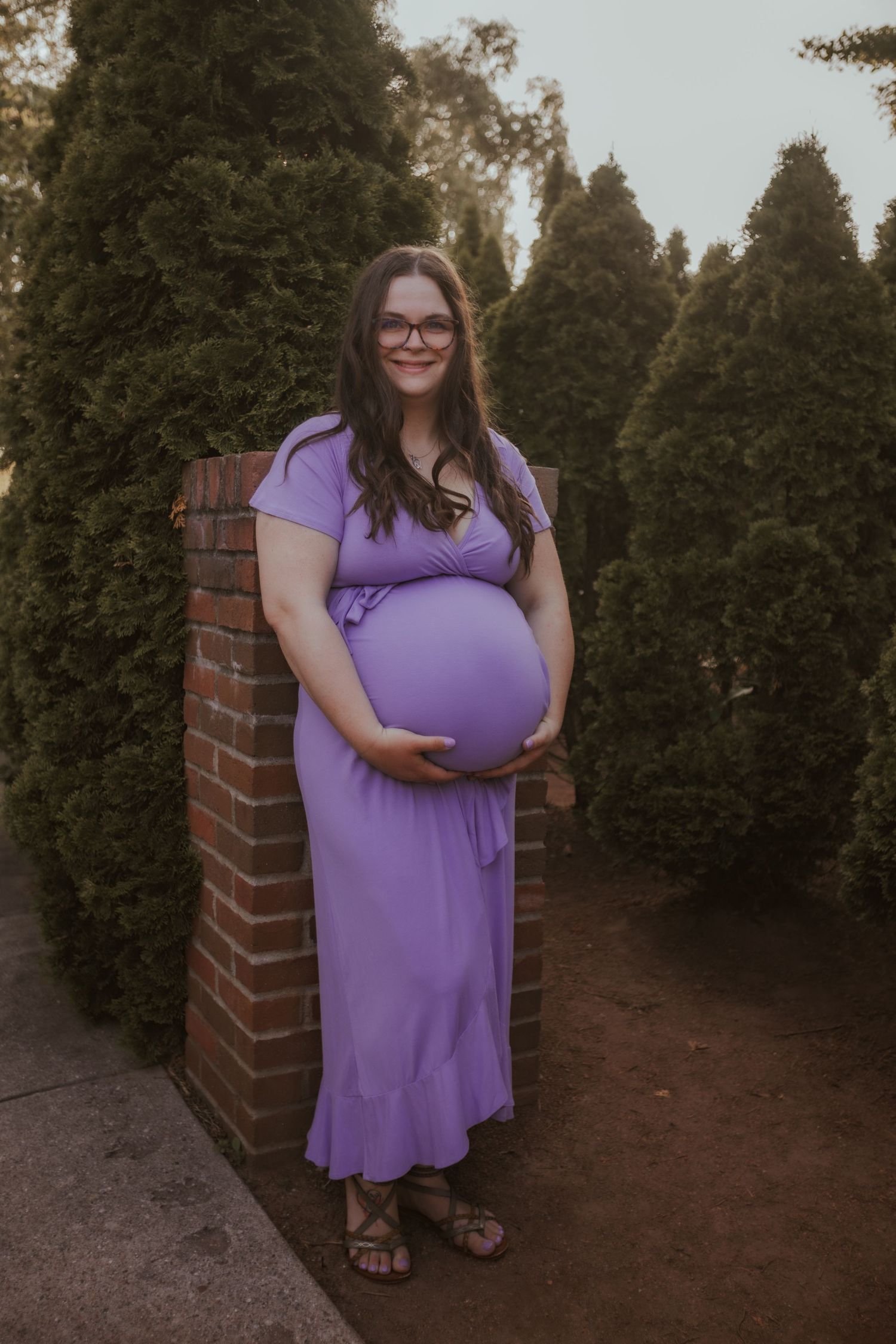 A series of photos showing someone in a flowing purple dress posing against a backdrop of evergreen trees.