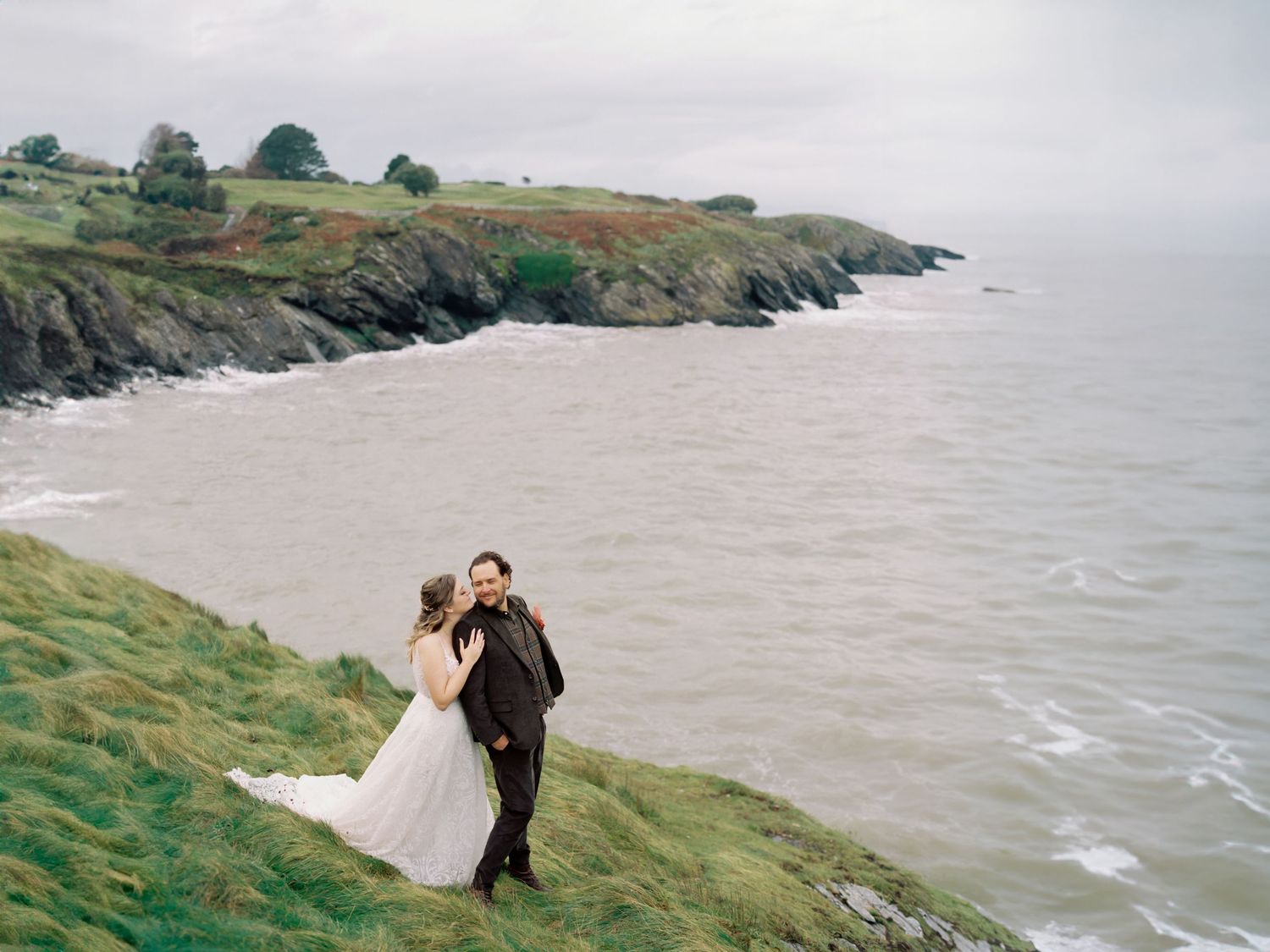 Dramatic coastal cliffside landscape with rolling green hills and misty ocean views.
