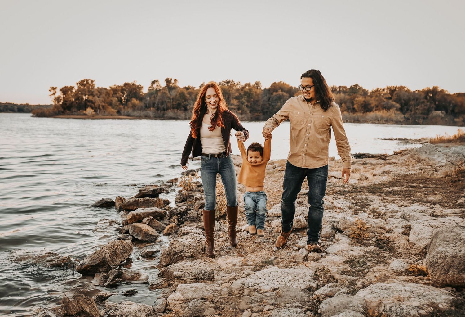 Toddler exploring lakeside rocks during a candid fall family photo session.