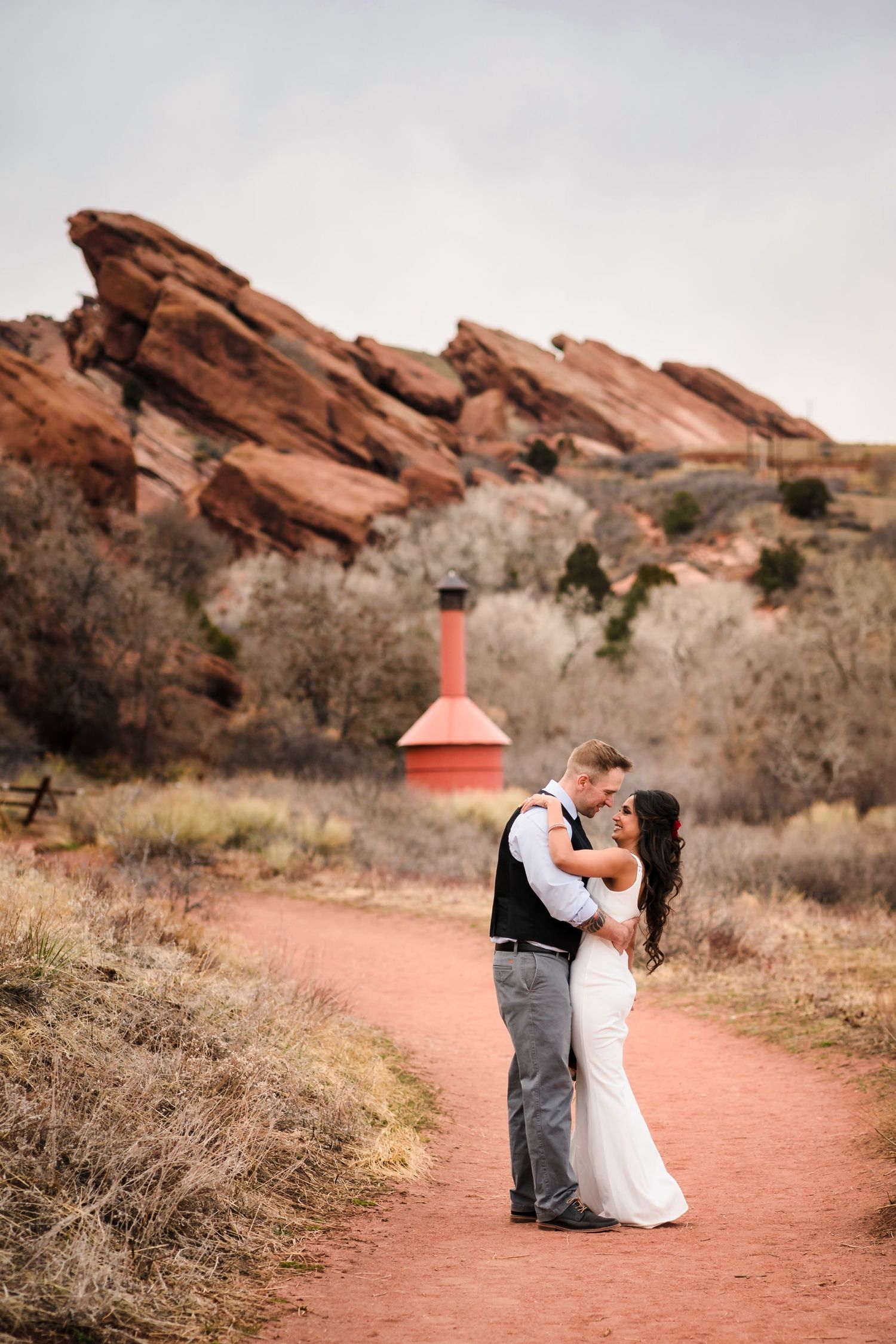 A couple embraces in a romantic dance pose against the backdrop of Red Rocks Park's stunning sandstone formations.
