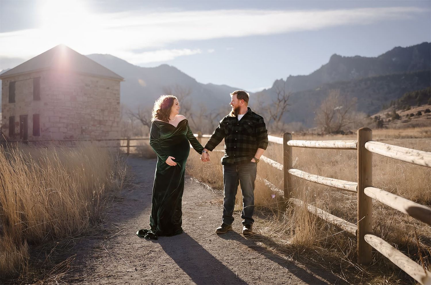 Denver maternity photography session of a couple holding hands and looking at each other lovingly against the flatirons in Boulder, Colorado