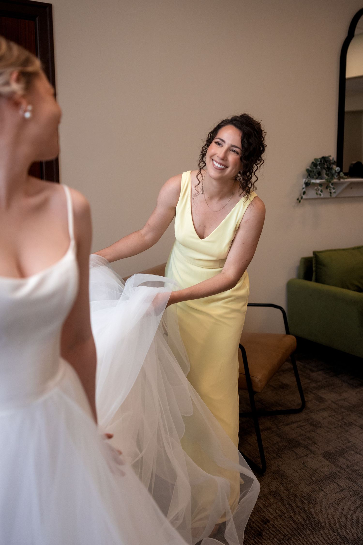 Two people dancing and twirling in white and yellow dresses in a room with a green couch.
