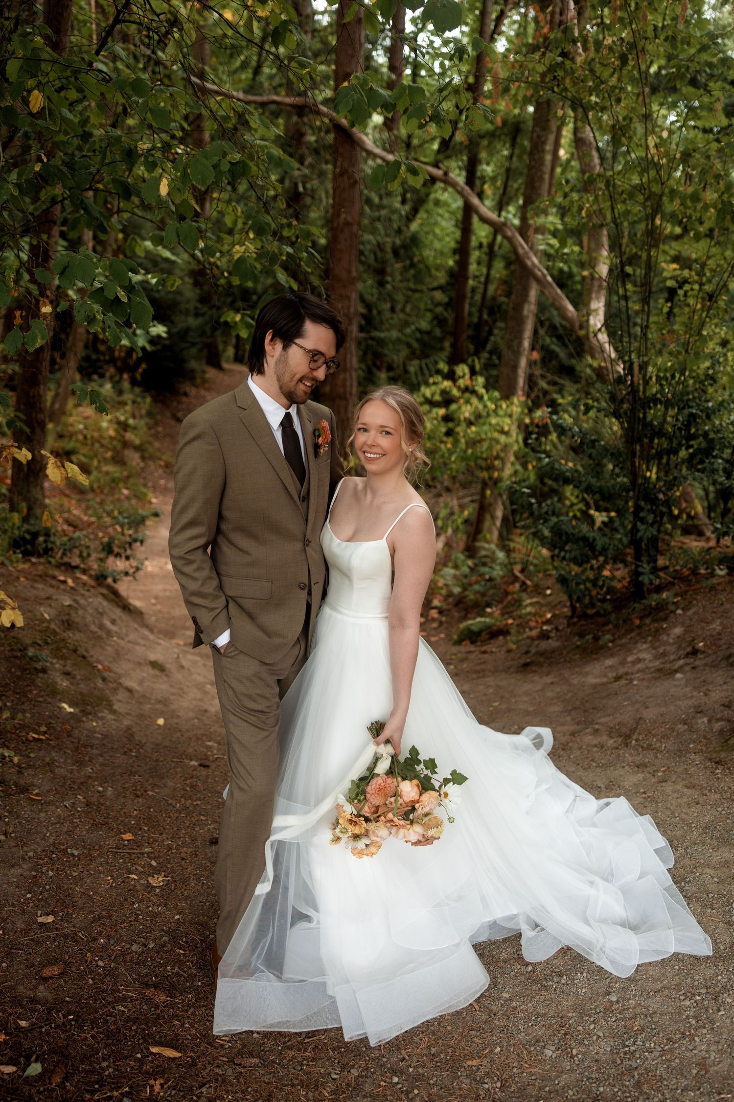 A romantic wedding photoshoot on a wooded trail with flowing white dress and autumn scenery.