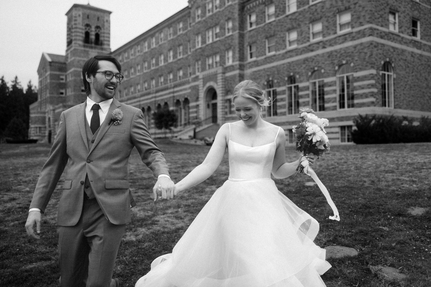Black and white portrait of wedding couple in front of historic architecture.