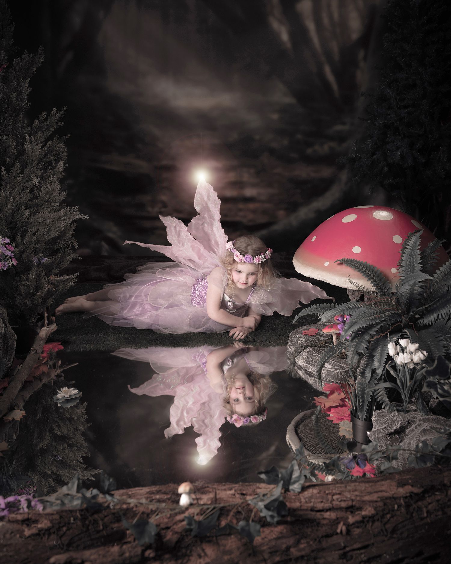 Enchanting fairy photo with a pink reflection in dark water next to a red and white spotted mushroom in a mystical forest scene.