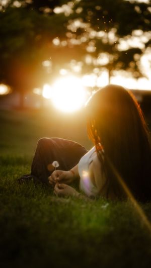 Silhouetted figure resting on grass during magical golden sunset.