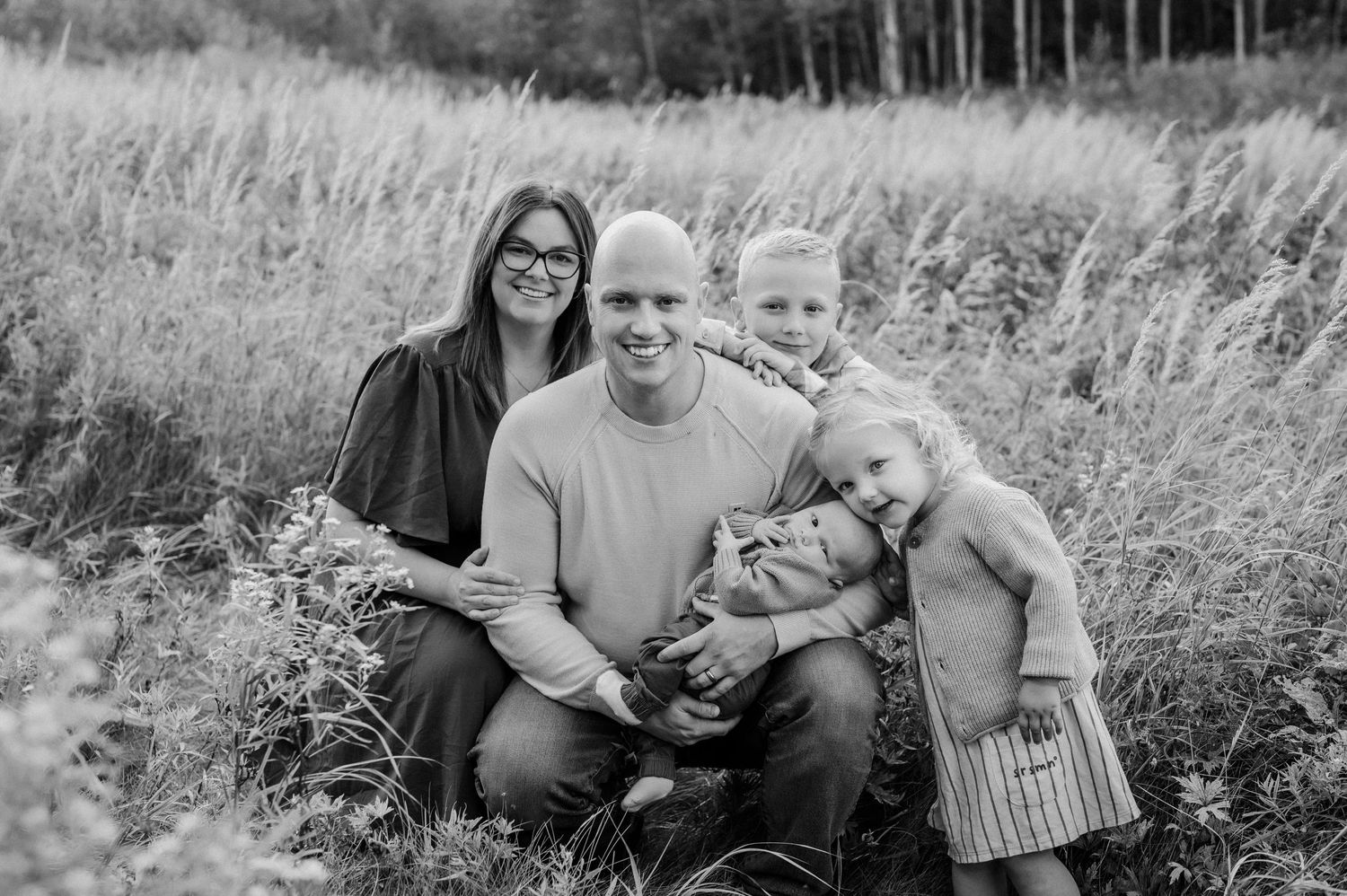 Natural family portraits taken in a meadow with rustic woodland backdrop.