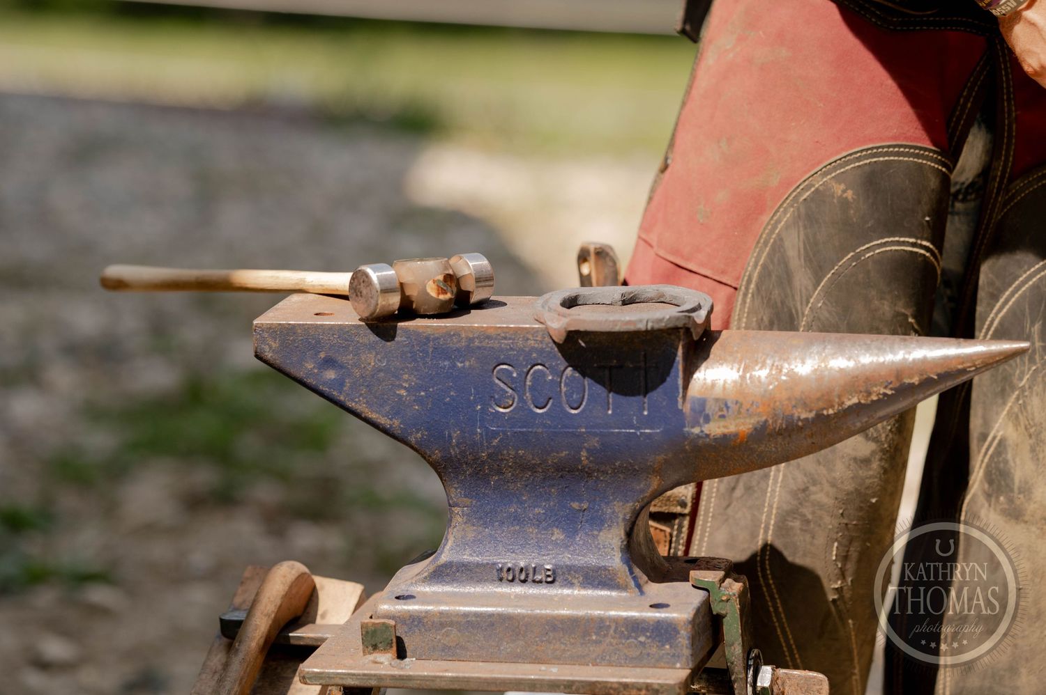 Close-up of a vintage Scott brand anvil mounted on farm equipment.