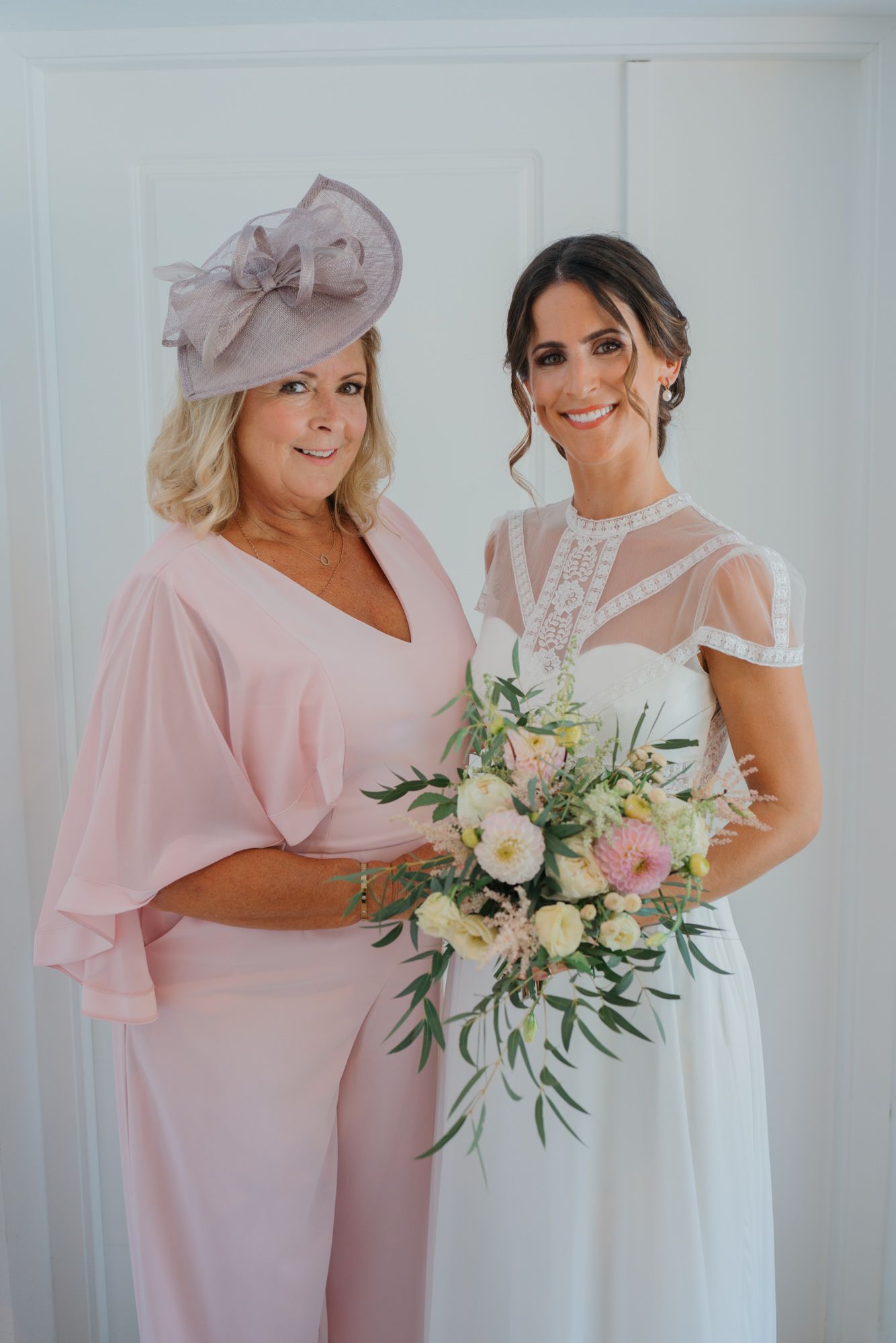 Wedding photo featuring pink and white floral bouquet and elegant formal attire.