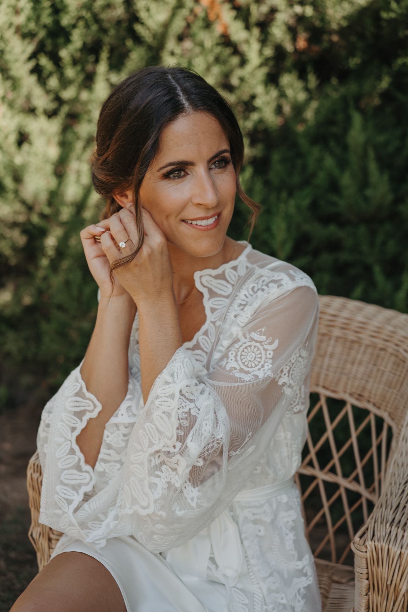Elegant lace wedding robe detail in outdoor setting with wicker chair.