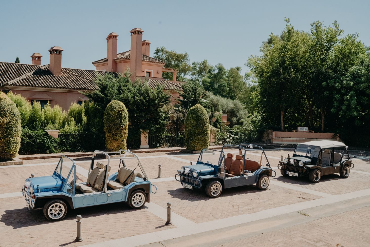 Row of colorful vintage convertible cars parked outside Mediterranean villa.