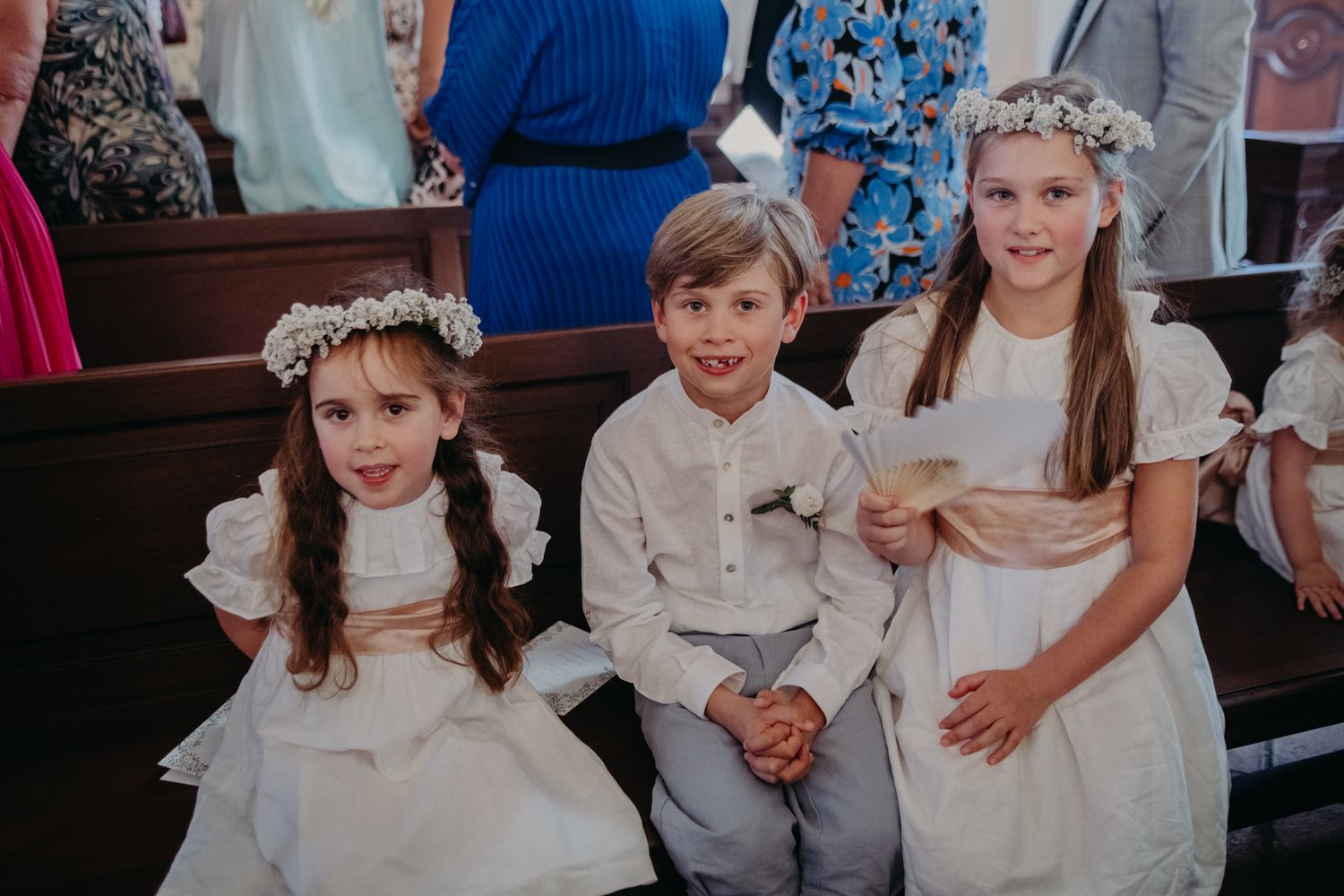 Children in white formal attire at church ceremony.