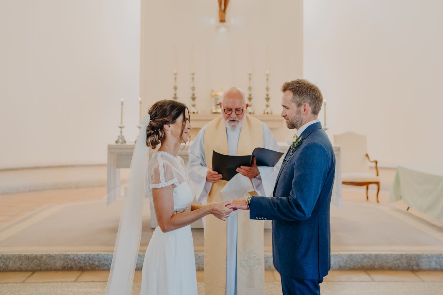Traditional wedding ceremony taking place at white church altar.