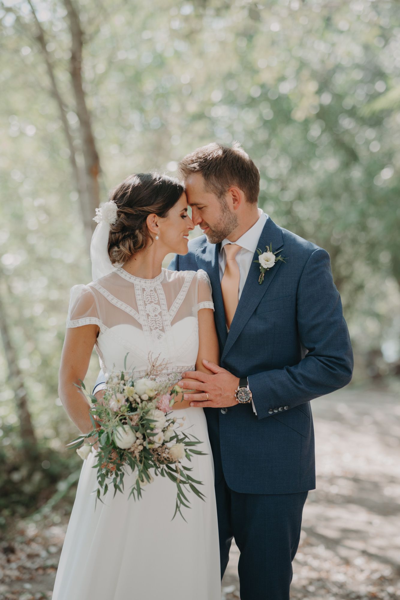 Intimate moment captured between newlyweds in a sunlit forest setting.