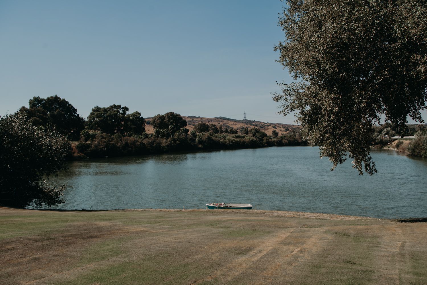 Scenic lakeside view with mountains and a boat dock under blue skies.