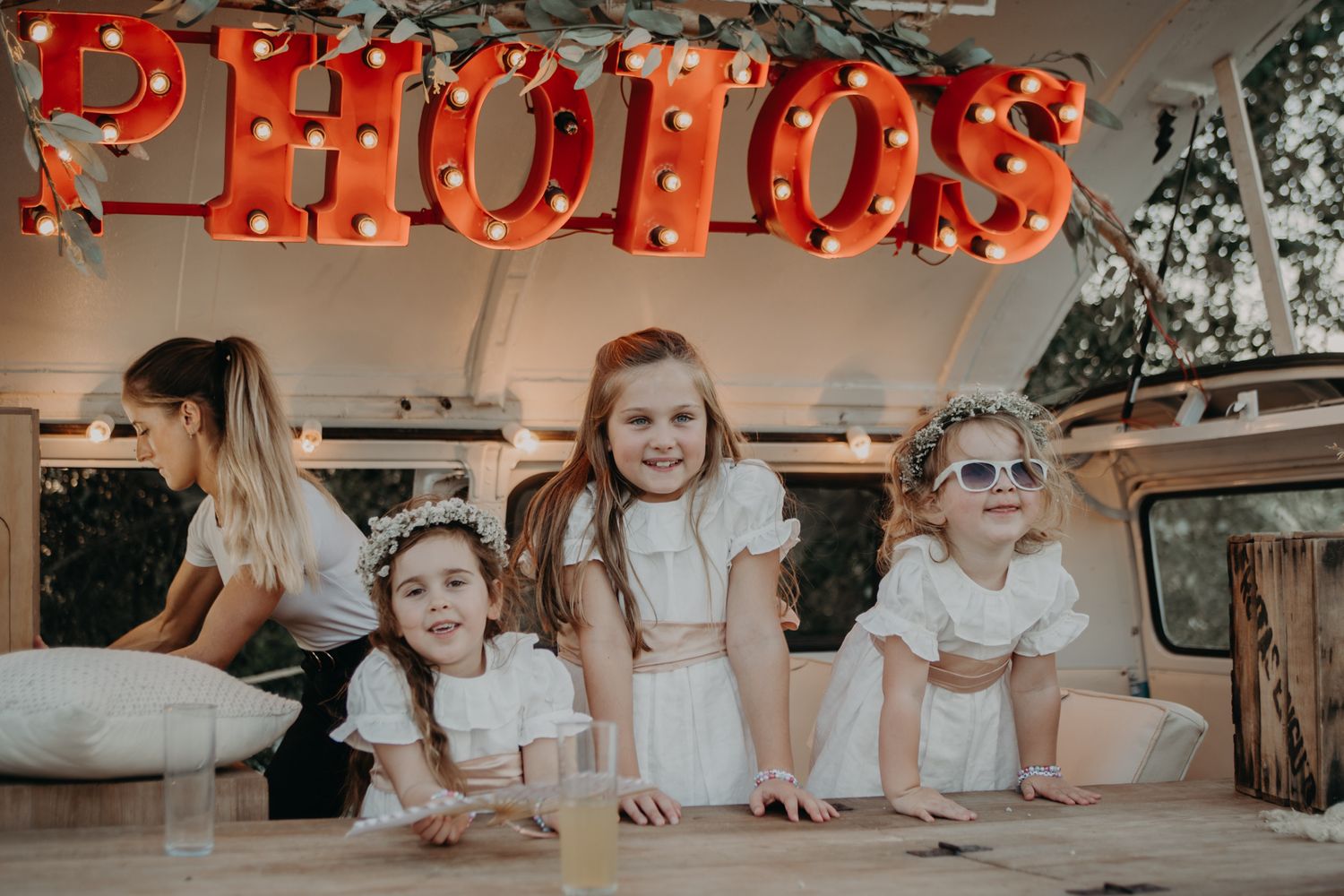 Vintage photo booth setup with illuminated red letters spelling 'PHOTOS' and decorative styling.