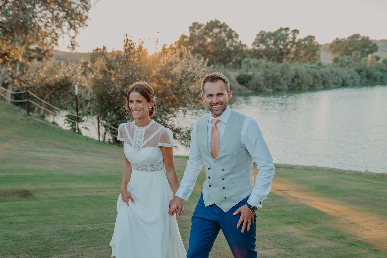 A sunset wedding portrait by a lake with golden evening light illuminating the scenic outdoor setting.