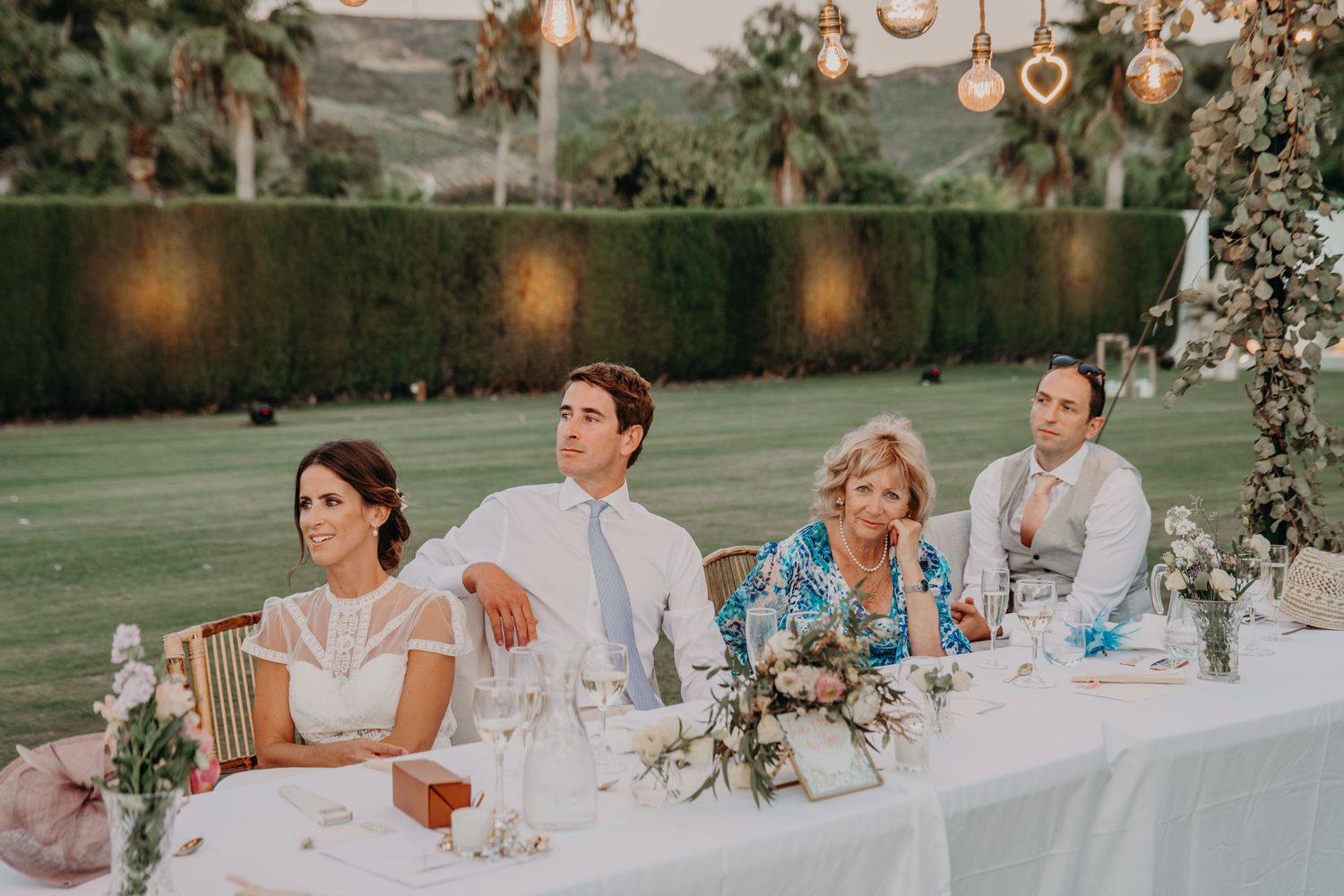 Elegant wedding reception head table setup outdoors with floral centerpieces and mountain views.
