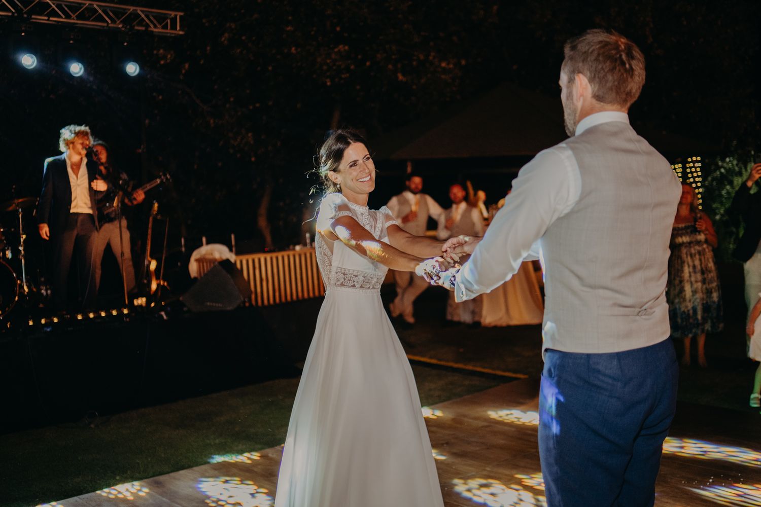 Bride and groom share their first dance under romantic lighting at evening reception.