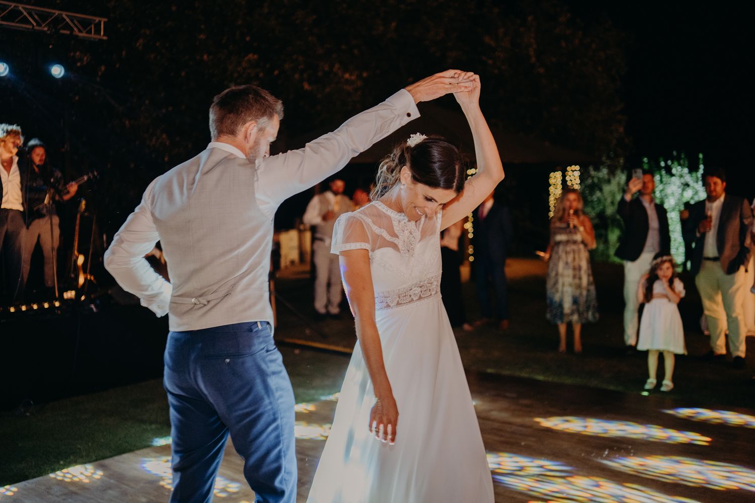 A couple dances together on an illuminated dance floor at a wedding reception during nighttime celebration.