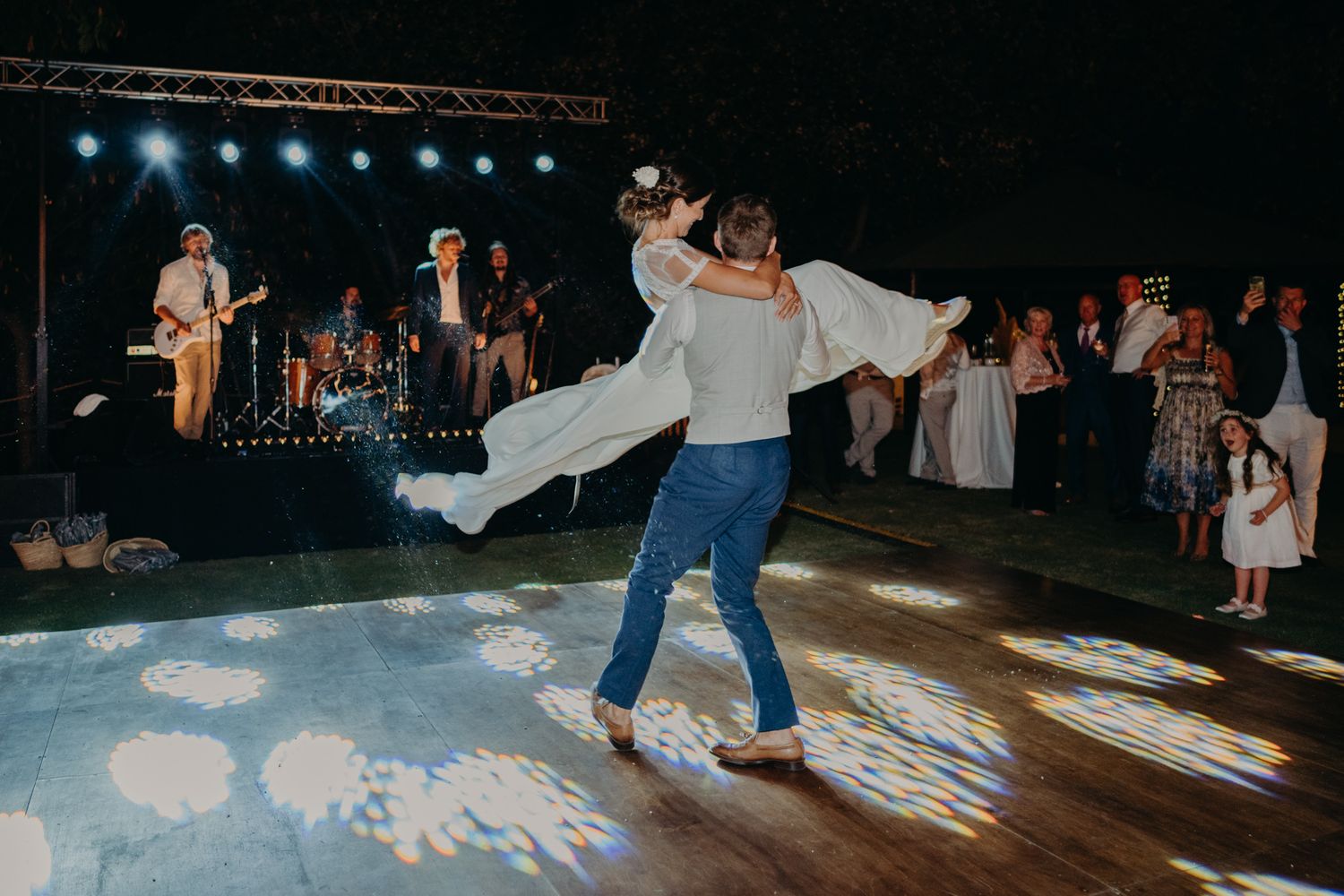 A festive dance moment captured during a wedding reception with guests and band in background.