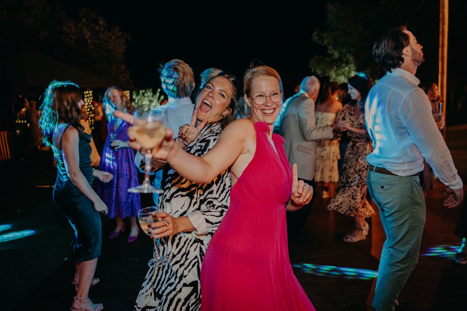Wedding guests enjoying themselves on the dance floor during an evening reception.