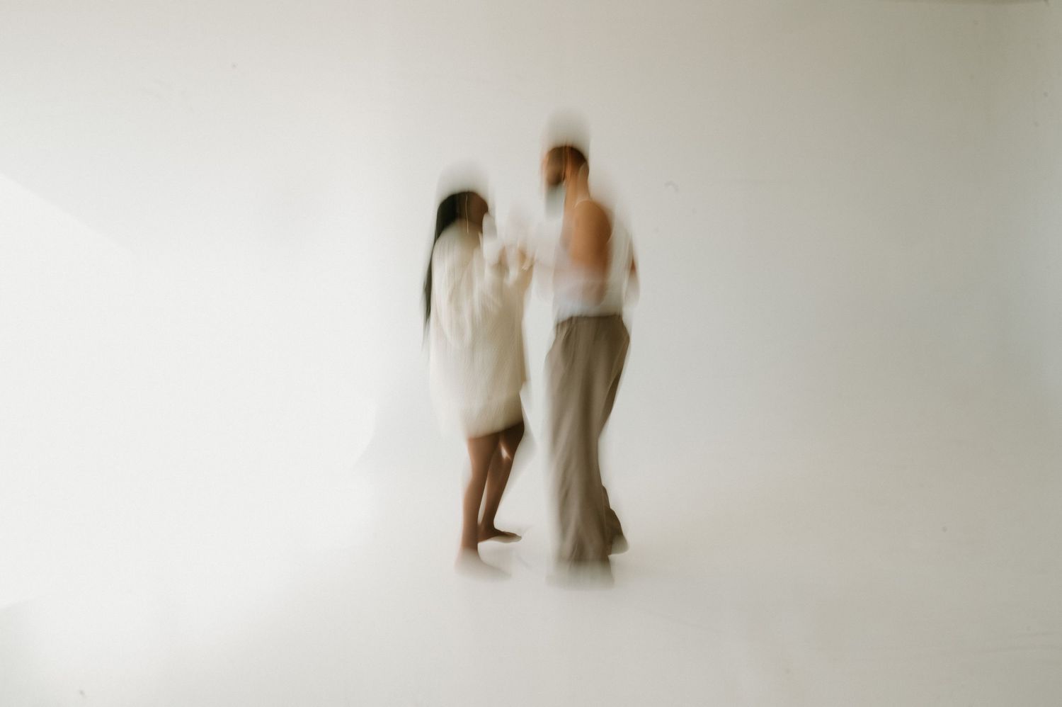 A flowing white wedding dress train trails elegantly through golden dried grass in a rustic outdoor setting.