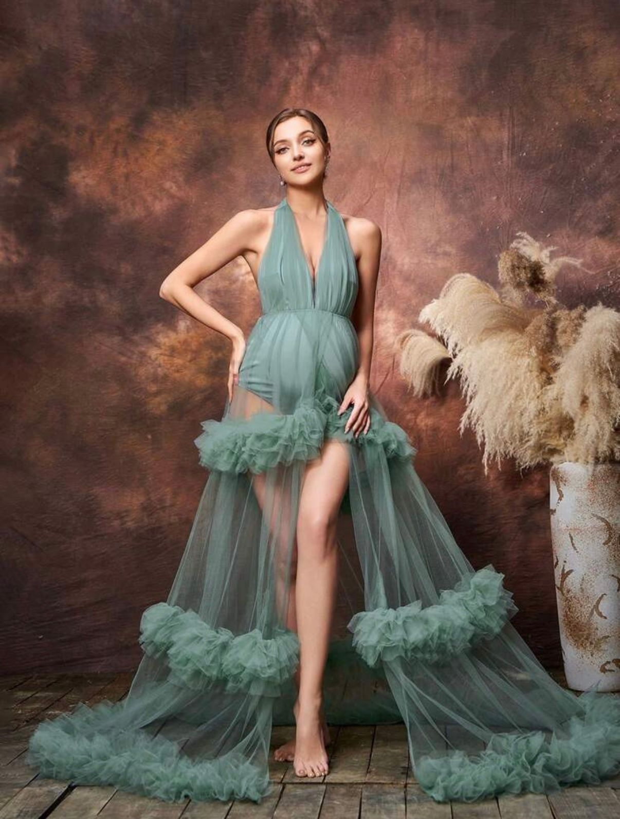 Elegant seafoam green tulle gown with dramatic ruffled details and thigh-high slit against a moody brown backdrop.