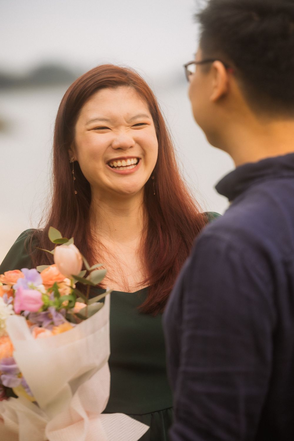 A couple shares a joyful moment together outdoors as they exchange a colorful bouquet of flowers.