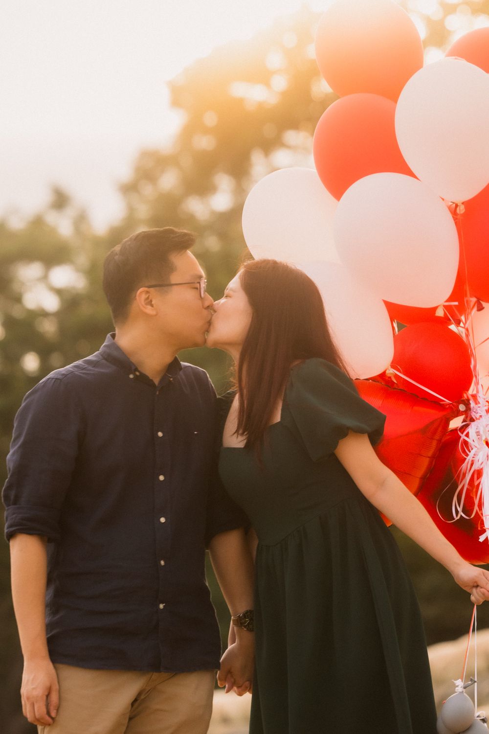 A romantic sunset moment with red and white balloons during an outdoor photo session.