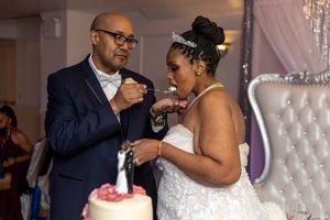 Wedding couple share cake during their reception while seated at an elegantly decorated table.