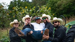 A group of guests wearing cowboy hats gathered outdoors at a rustic country celebration.