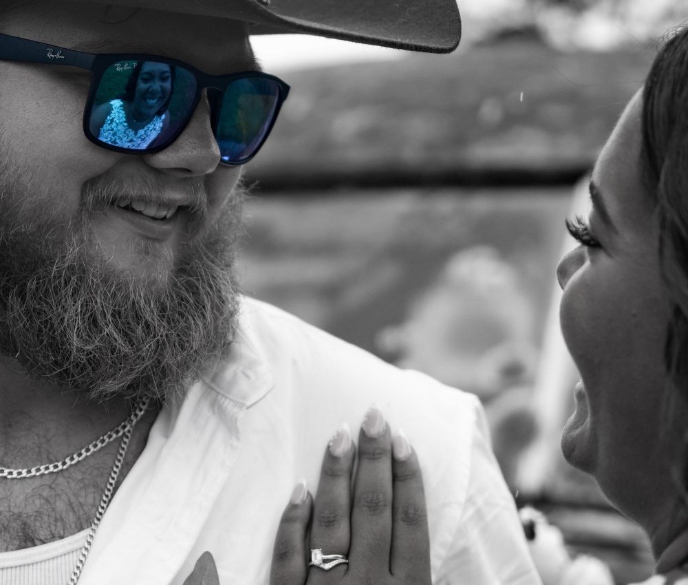 Black and white close-up photo showing sunglasses and casual attire at an outdoor gathering.
