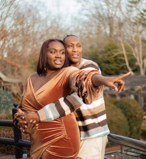 Two people share a joyful moment together outdoors while pointing into the distance on a sunny autumn day.