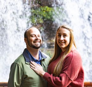 A couple shares a joyful moment outdoors wearing casual fall clothing in warm natural lighting.