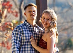 A happy couple embraces and laughs together against a bright blue sky background.