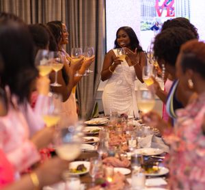 Group enjoying a celebratory dinner party with wine glasses raised in a toast at an elegant table setting.