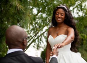 A joyful moment between a couple at their outdoor wedding ceremony with willow trees in the background.