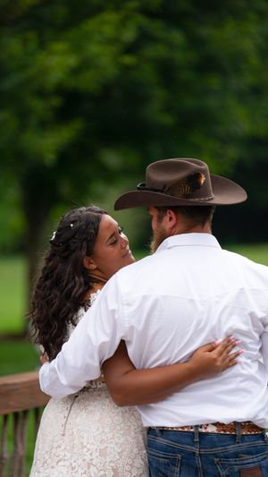 An intimate embrace shared between a couple, with one wearing a white dress and the other in western attire.