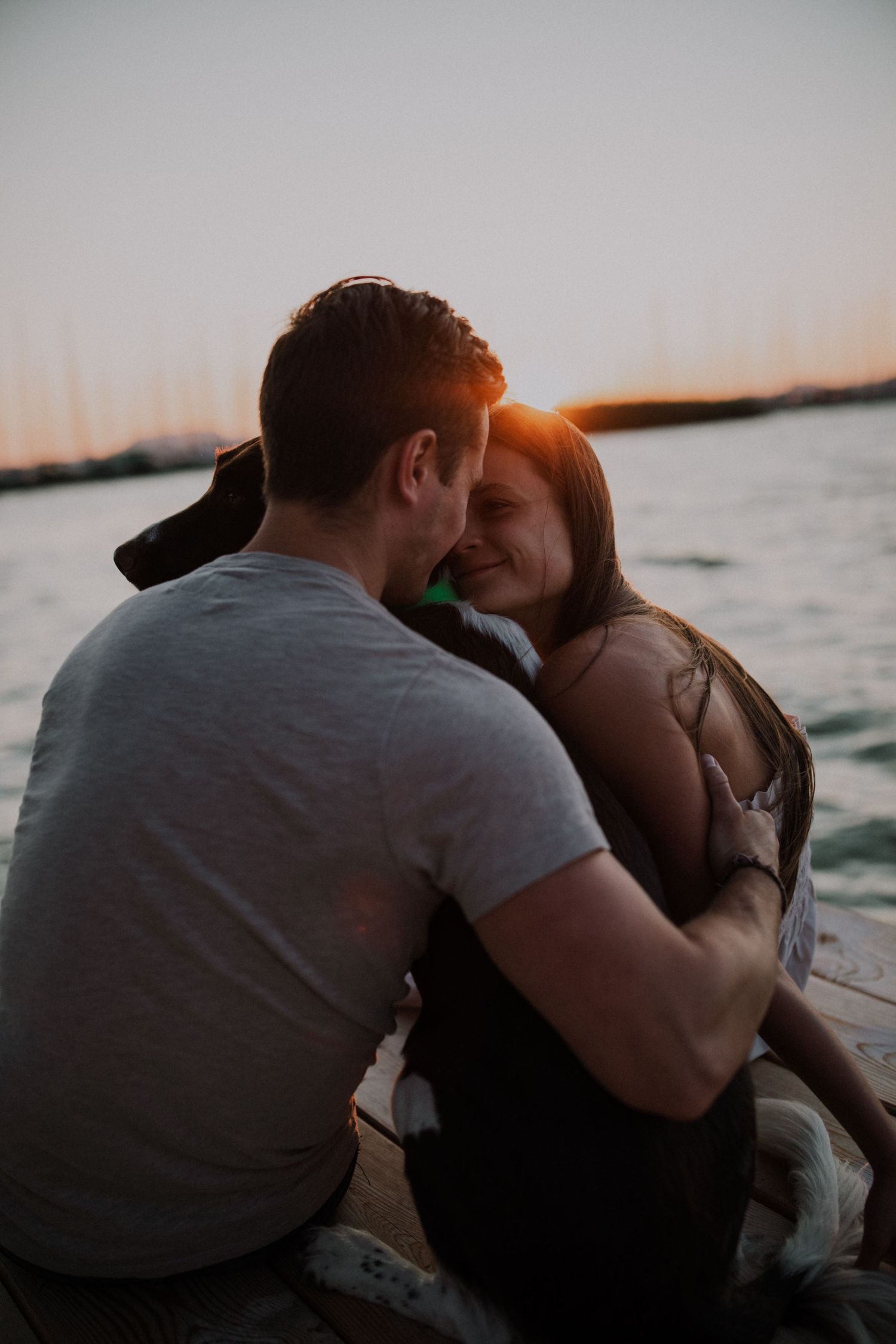 A couple shares an intimate moment at sunset by the water.