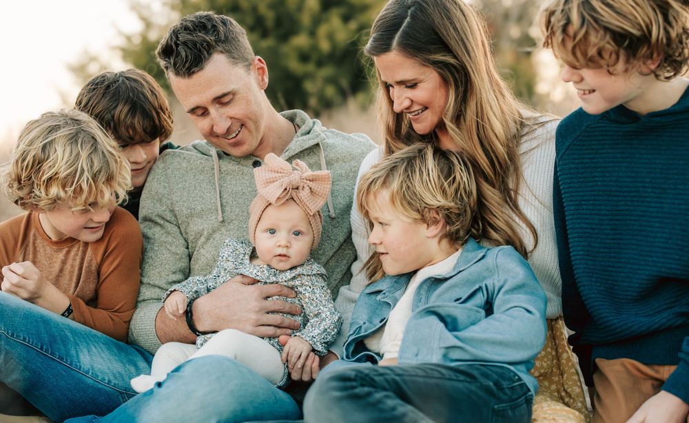 A family sits together outdoors enjoying a candid moment of laughter and connection in natural lighting.