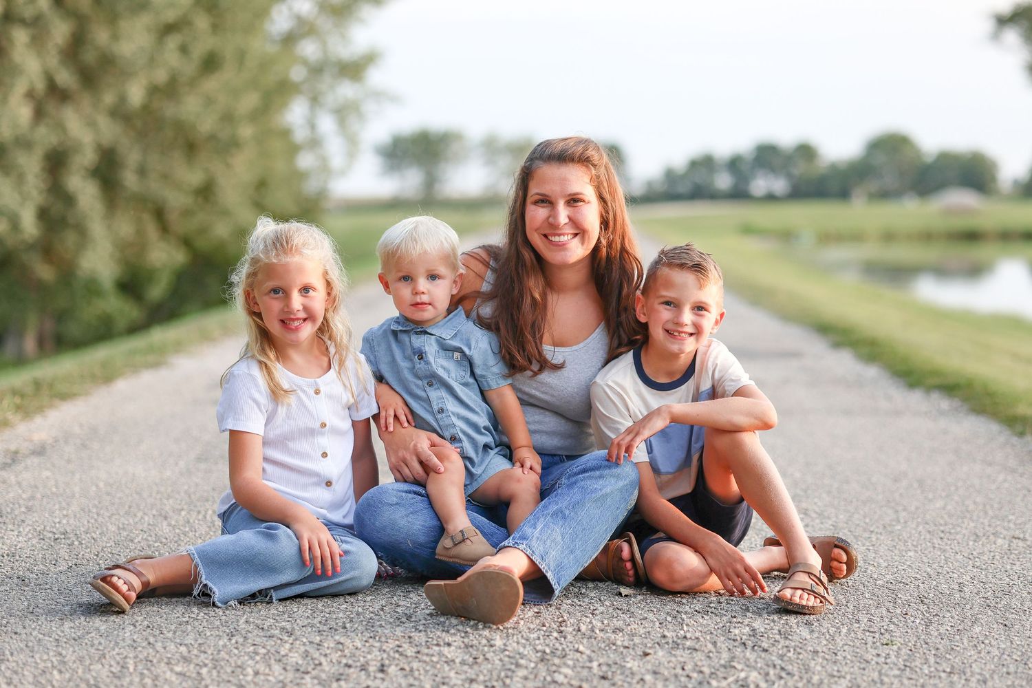 Springfield, IL family photographer captures a mom with her three kids on a gravel path in Central, IL
